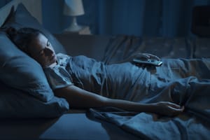 Woman sleeping with light of her TV on